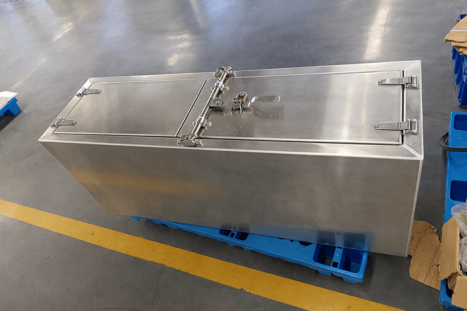 Heavy-duty aluminum truck tool box with stainless steel latches placed on pallet in factory workshop, OEM truck accessory storage box for fleet and commercial vehicles