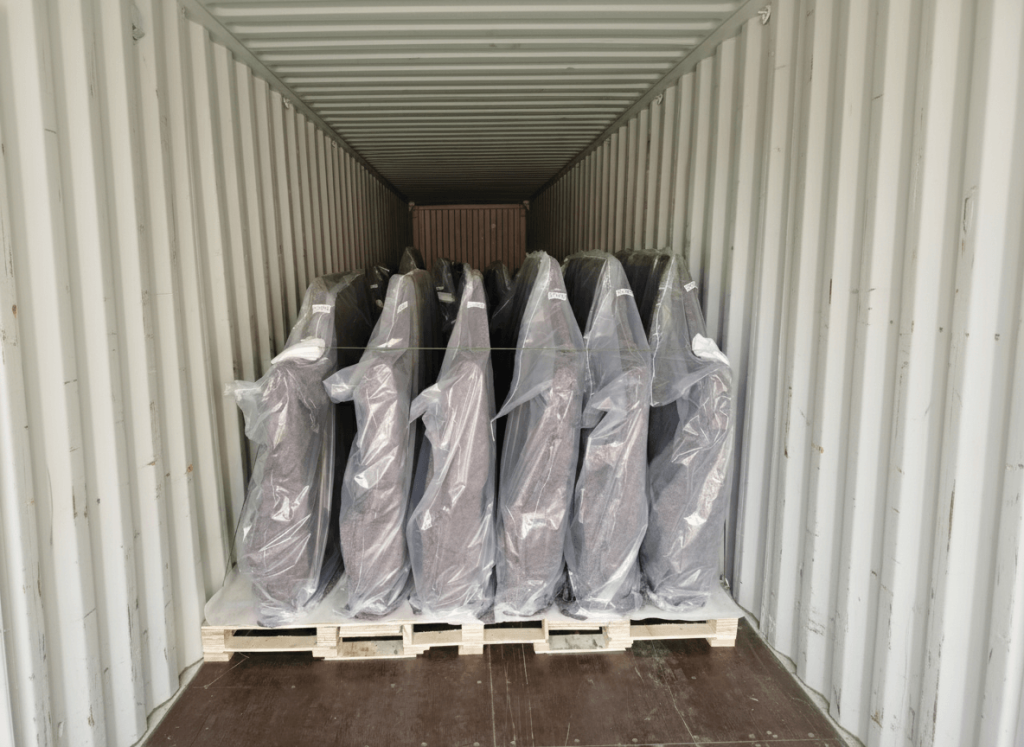 Palletized heavy-duty truck bumpers wrapped for protection and secured inside a shipping container for bulk OEM export