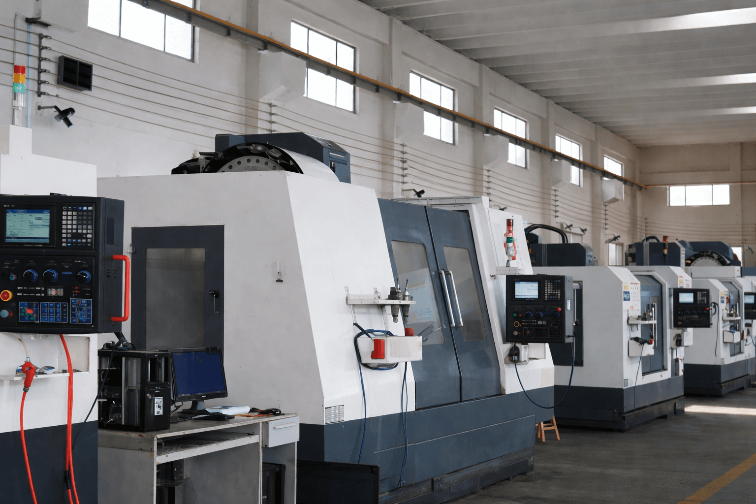 CNC machining workshop with multiple industrial milling machines aligned in a factory, demonstrating OEM build-to-print manufacturing and batch production capability for heavy-duty truck components