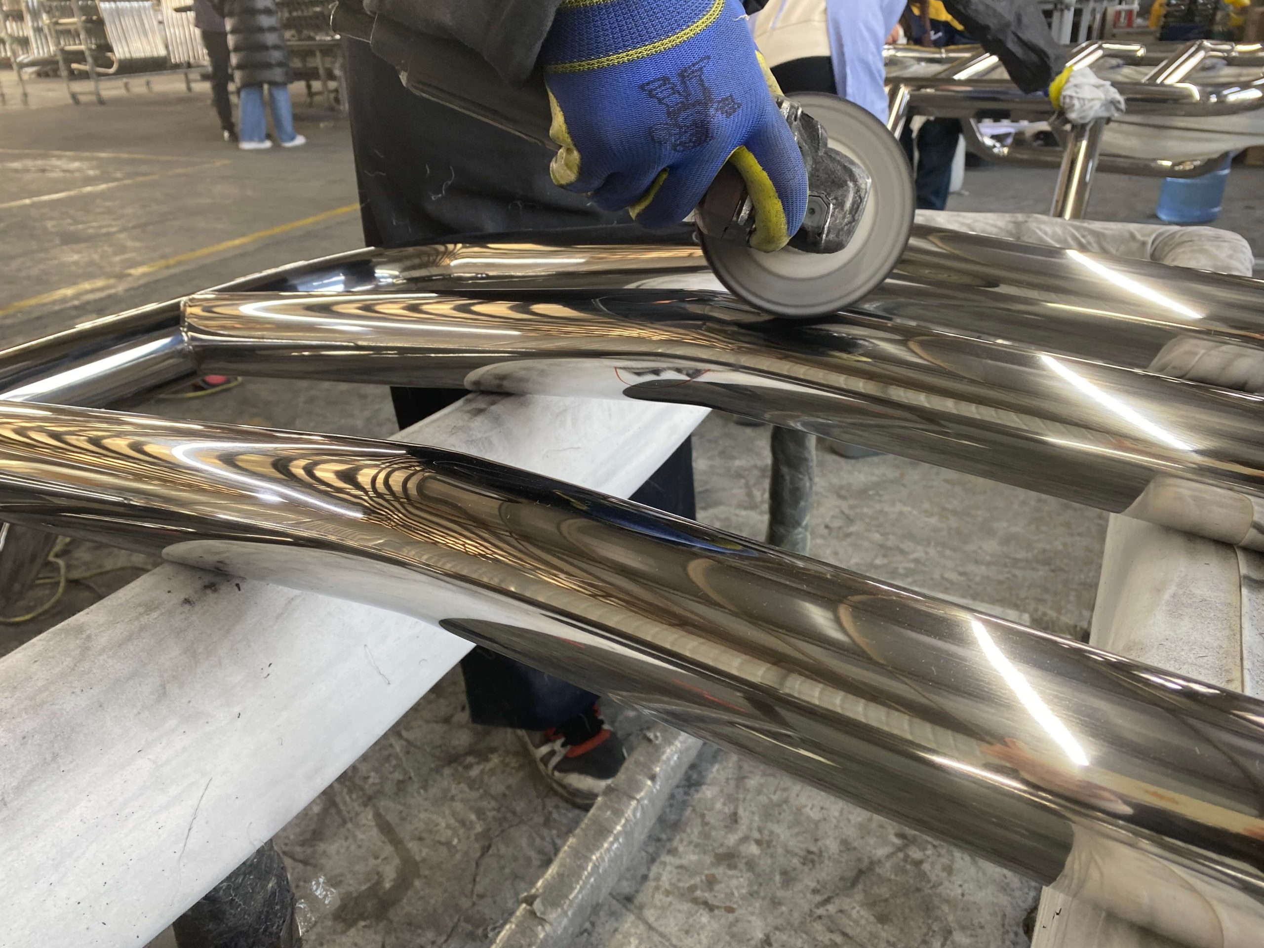 Manual polishing of stainless steel tubular components using handheld grinder in manufacturing process