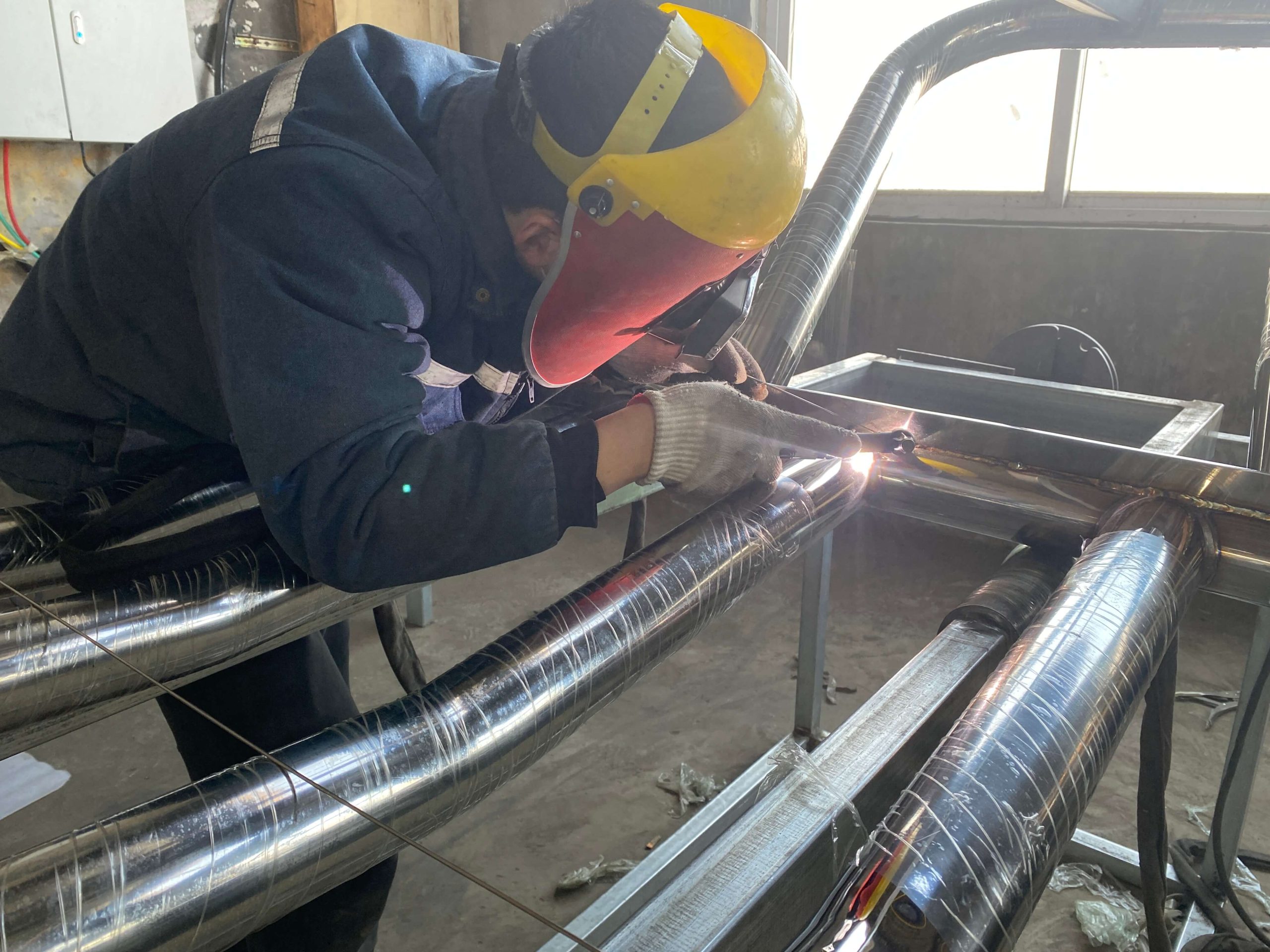 Manual TIG welding of stainless steel tubular components during truck accessory fabrication