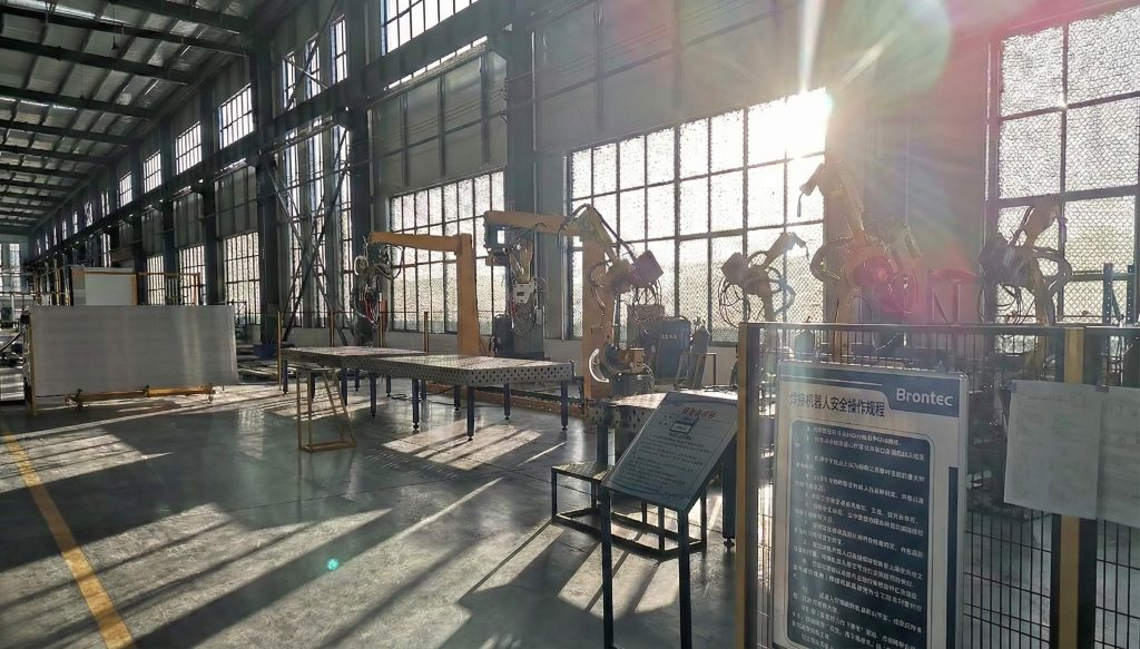 Heavy-duty truck accessories manufacturing workshop with robotic welding arms and automated production lines inside a large-scale industrial factory